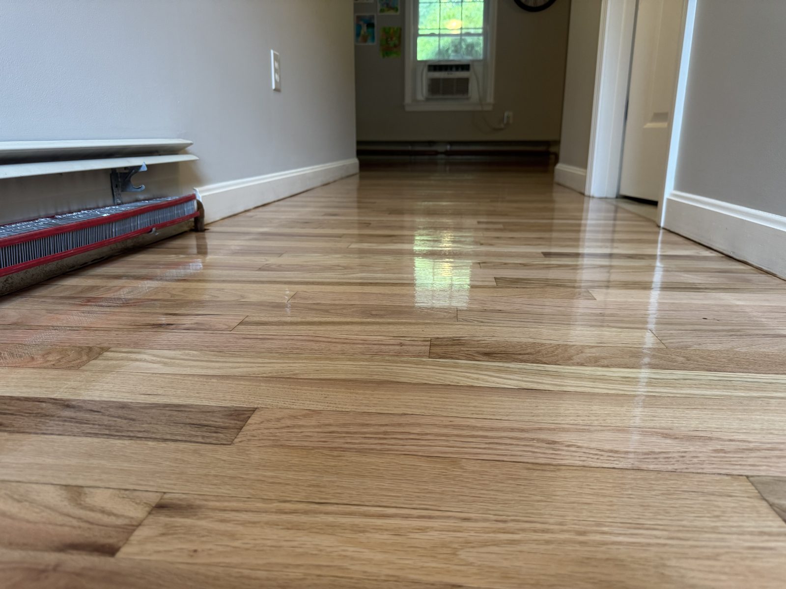 After hardwood floor refinishing in Coventry, Rhode Island — same hallway sanded to bare wood and finished with three coats of water-based polyurethane, clean natural hardwood