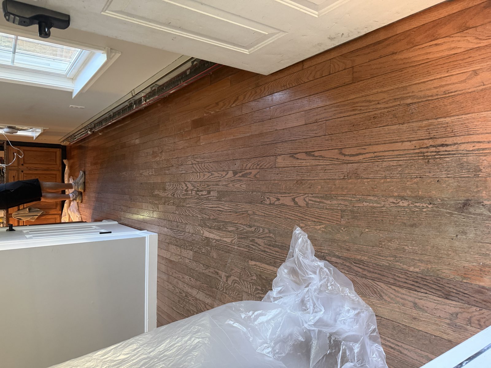 Before hardwood floor refinishing in Coventry, Rhode Island — worn, scratched prefinished hardwood hallway with a dull, discolored older stained finish