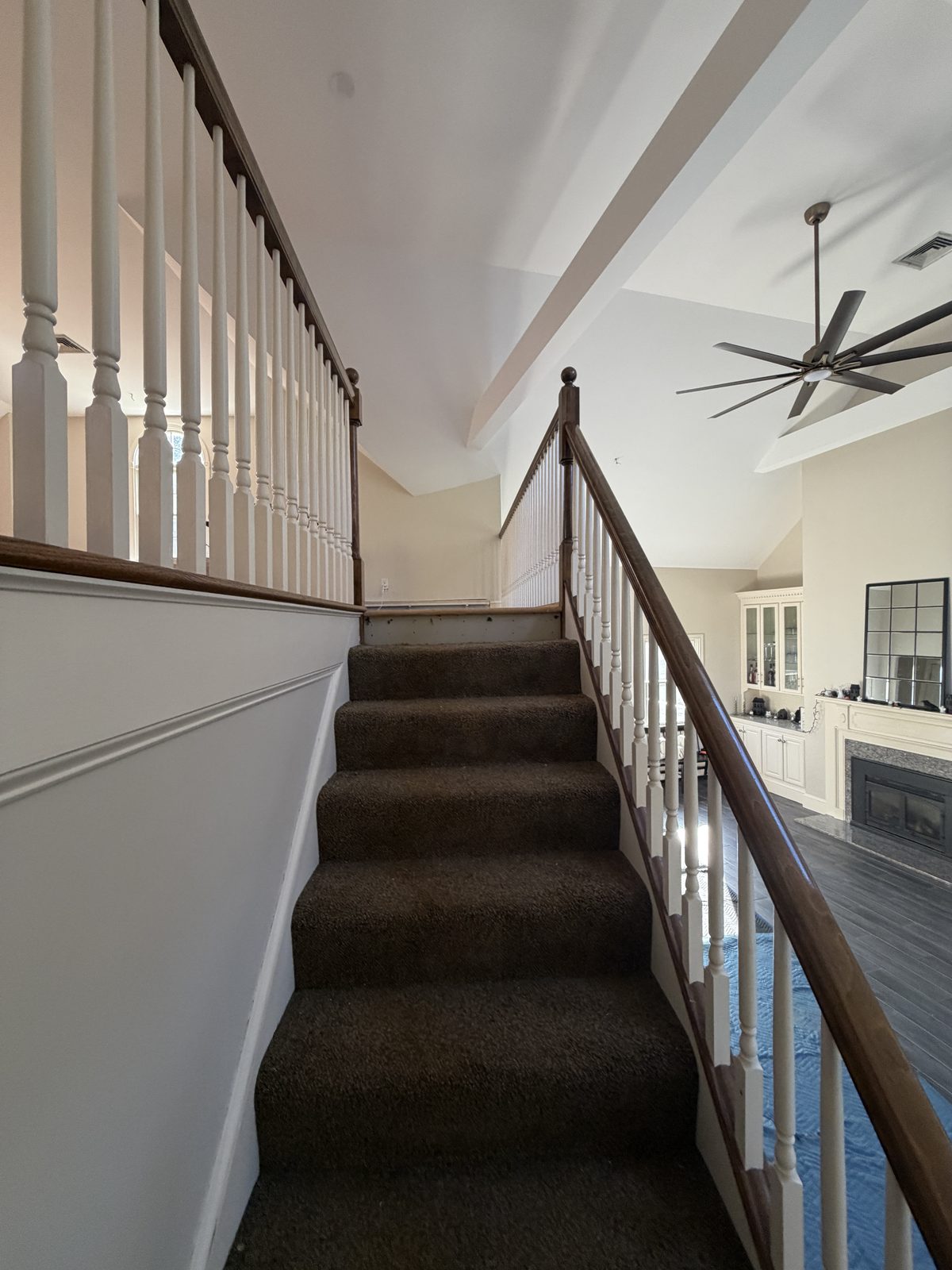 Original carpeted steps with turned white balusters and a dark stained handrail before the Rehoboth staircase rebuild.