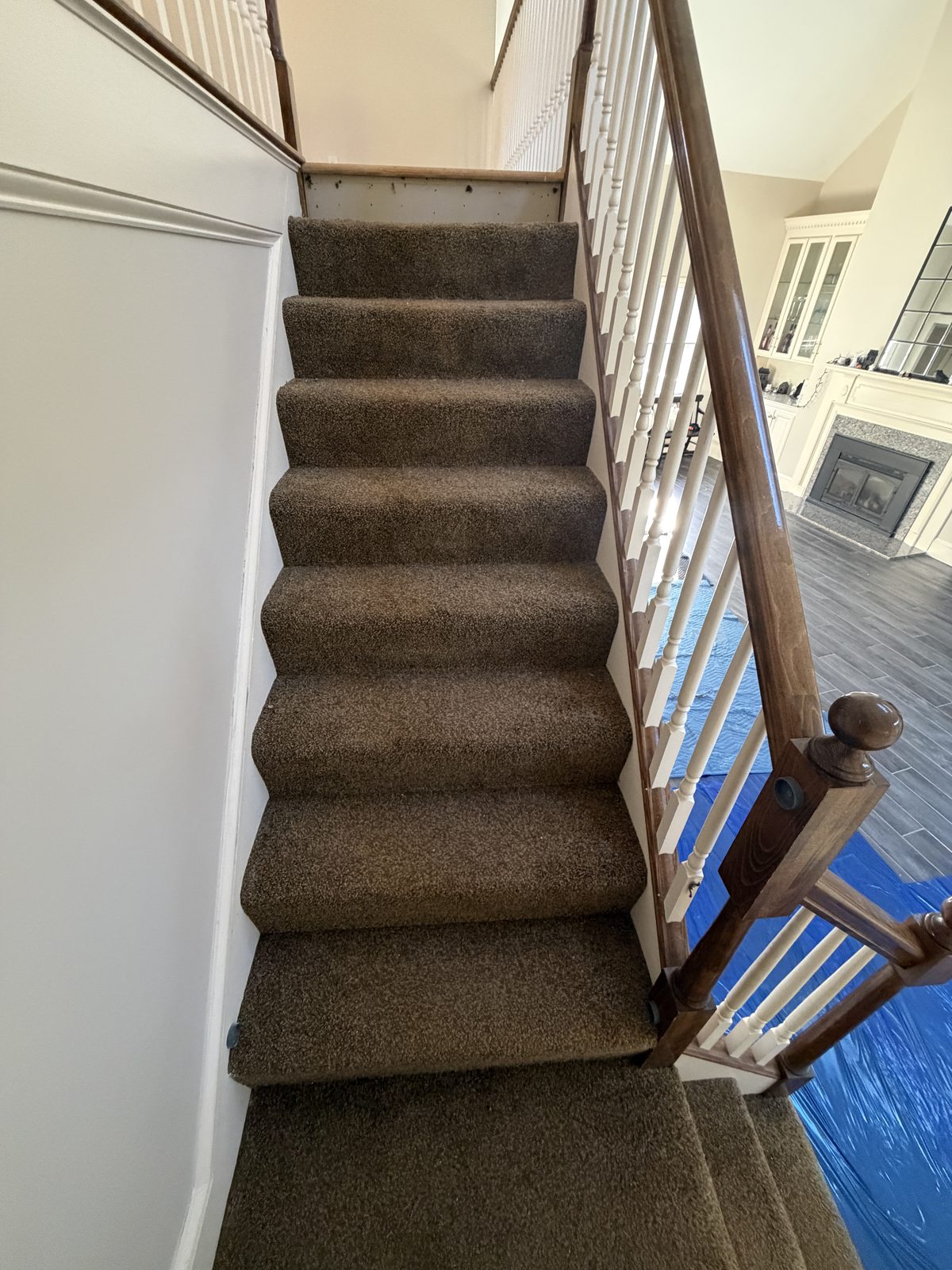 Angled view of the original carpeted steps and stained handrail before the custom staircase rebuild in Rehoboth, MA.